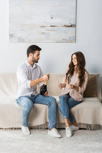 Knappe Man Opening Fles Champagne Terwijl Zijn Vriendin Zit Buurt — Stockfoto