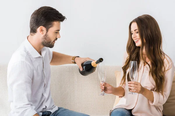 Young Man Pouring Champagne Glass While Sitting Couch Girlfriend Home — Stock Photo, Image