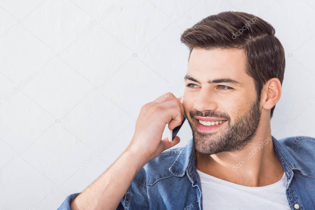 close up portrait of happy handsome man talking on smartphone and looking away at home