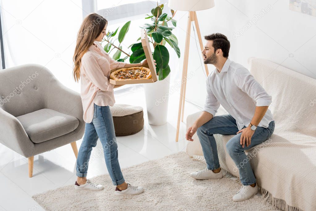high angle view of young couple with pizza in disposable box at home