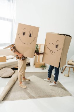 obscured view of couple with cardboard boxes on heads holding hands at new house, moving home concept clipart
