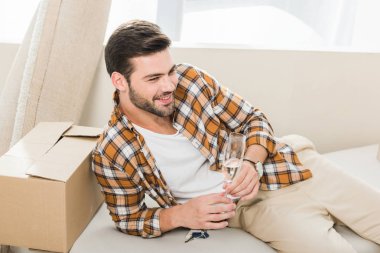 Yeni ev, hareketli ev concept, kanepede oturan şampanya ile adam gülümseyen
