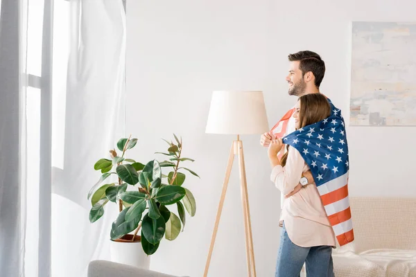 Sidebillede Unge Par Dækket Med Amerikansk Flag Stående Derhjemme - Stock-foto