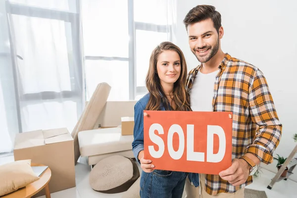 Retrato Sonriente Joven Pareja Sosteniendo Vendido Tarjeta Roja Casa Con —  Fotos de Stock