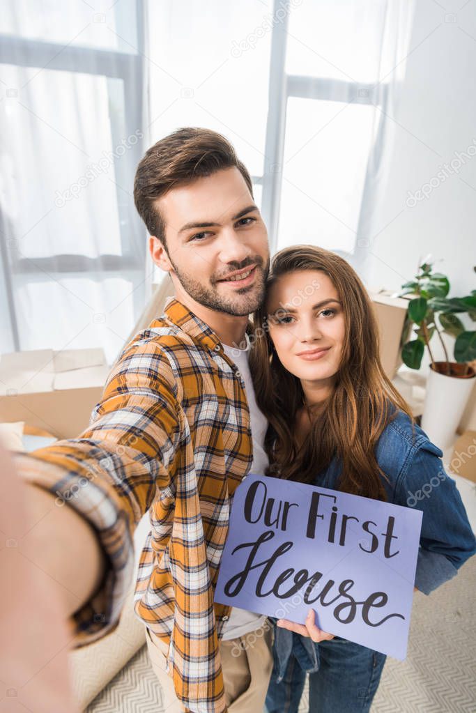 camera point of view of smiling couple with our first house card taking selfie together at new home