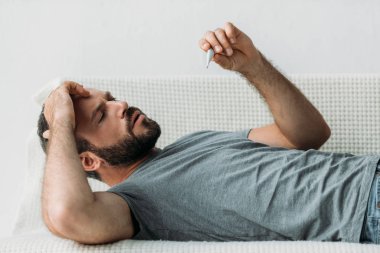koltukta yalan ve termometre tutan hasta sakallı adam