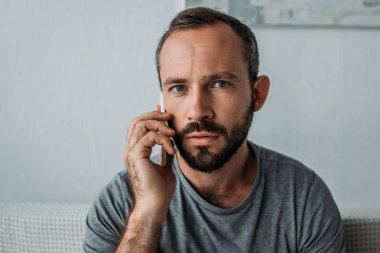 Smartphone ile konuşmak ve kameraya bakarak sinirli sakallı adam 