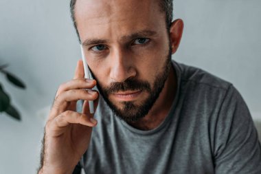 Smartphone ile konuşmak ve kameraya bakarak üzgün sakallı adam 