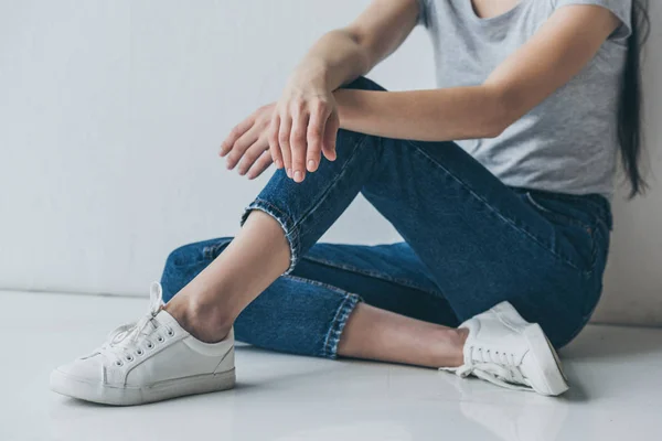 Tiro Cortado Menina Jeans Sentado Chão Perto Parede Cinza — Fotografia de Stock
