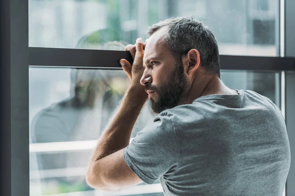 ウィンドウで傾いているとそれを通して見る動揺のひげを生やした男 — ストック写真