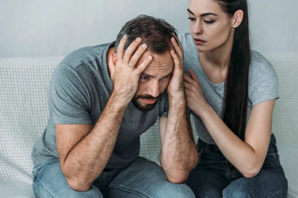 Genç kadın kanepede oturan depresif sinirli erkek destekleyen  