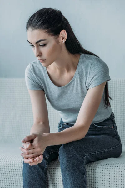 Aufgebrachte Junge Brünette Frau Sitzt Auf Couch Und Schaut Nach — Stockfoto