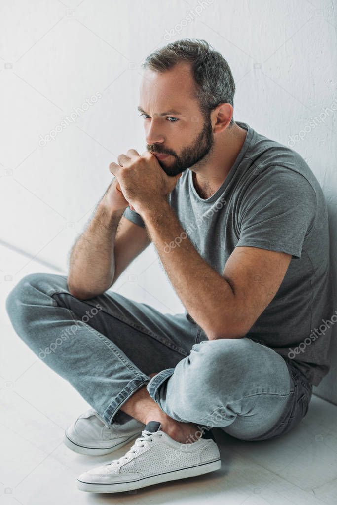 high angle view of sad bearded man sitting in floor and looking away