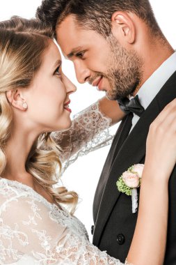 Genç gelin ve damadın kucaklayan ve birbirlerine beyaz izole bakarak yakın çekim portre