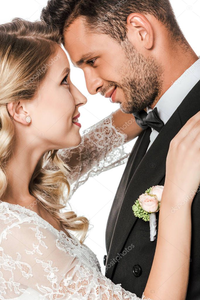 close-up portrait of young bride and groom embracing and looking at each other isolated on white