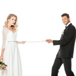 Felice giovane sposo con catena e guinzaglio sposa isolato su bianco