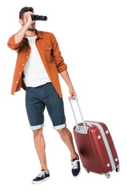 mutlu genç adam dürbün ve Bagaj yürüyüş ve uzak üzerinde beyaz izole arıyorsunuz