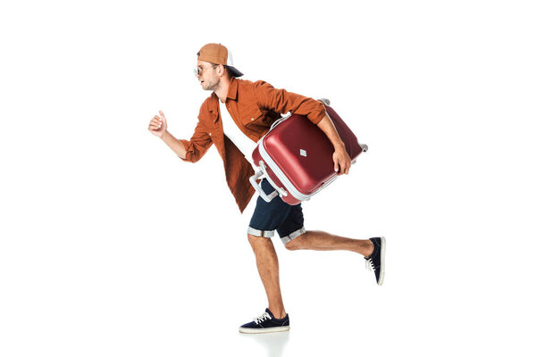 side view of handsome man running with luggage isolated on white