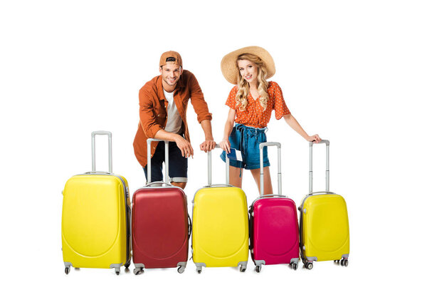 smiling newlywed couple with arranged suitcases around isolated on white