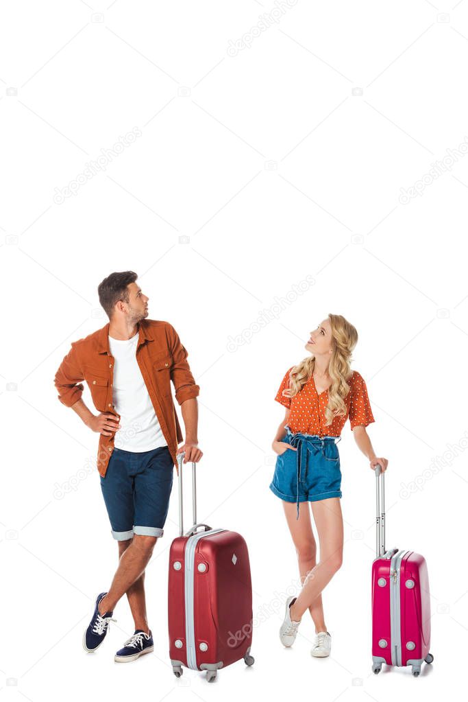 young couple with luggage looking up isolated on white