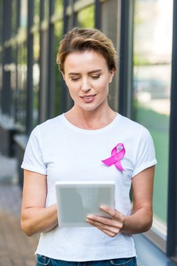 woman with pink ribbon on t-shirt using digital tablet, breast cancer awareness concept      clipart