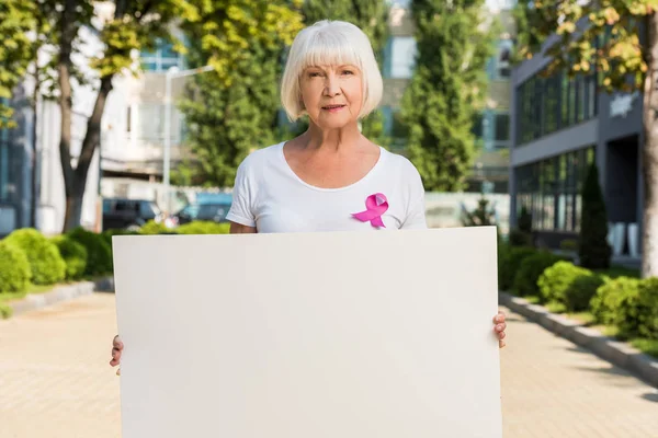 Mulher Sênior Com Fita Rosa Segurando Cartão Branco Olhando Para — Fotografia de Stock