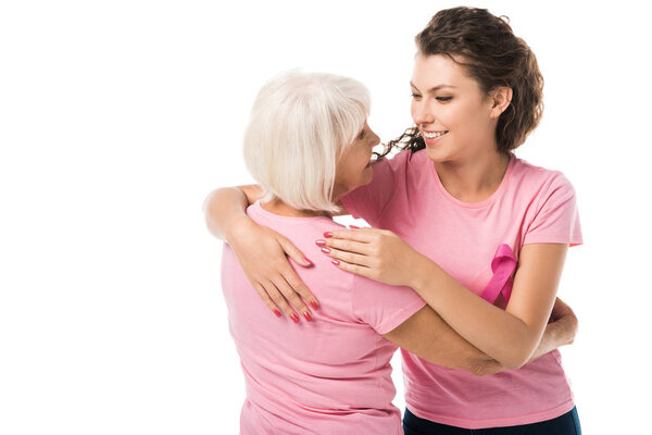 women in pink t-shirts hugging and smiling each other isolated on white, breast cancer awareness concept