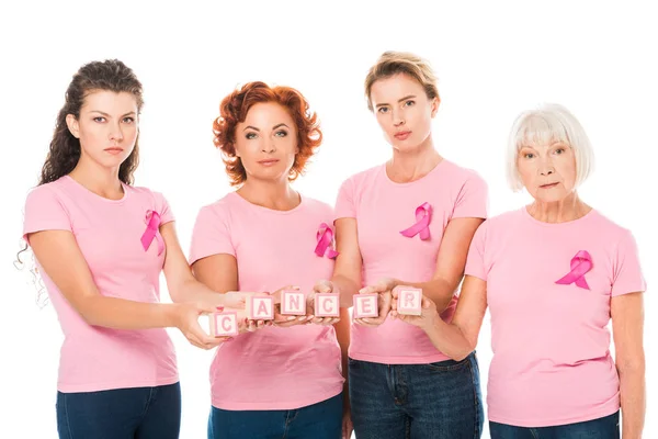 女性在粉红色 T恤与乳腺癌意识丝带持有立方体与词癌症 看着相机在白色隔离 — 图库照片