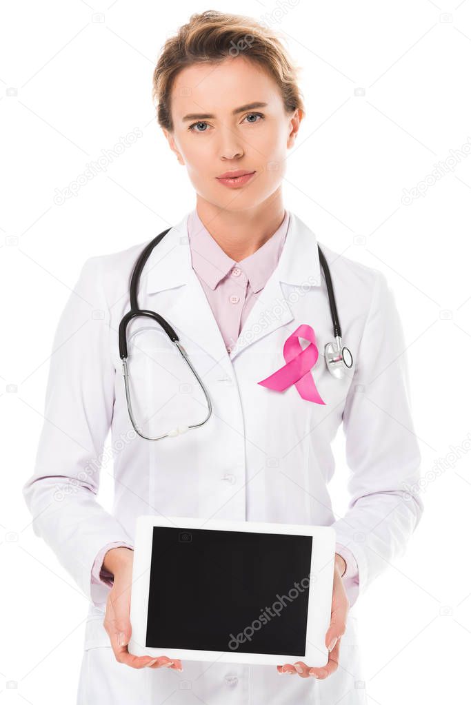doctor with pink ribbon holding digital tablet with blank screen and looking at camera isolated on white, breast cancer awareness concept  