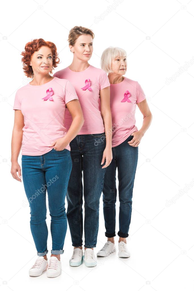 women with pink ribbons standing together and looking away isolated on white, breast cancer awareness concept 