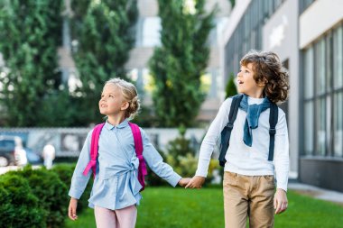 sevimli heyecan schoolkids ile el ele tutuşarak ve bakarken sırt çantaları