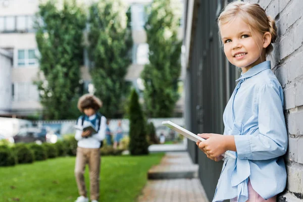 Roztomilá Malá Školačka Pomocí Digitálních Tabletu Usmívá Kameru Naklánět Cihlovou — Stock fotografie