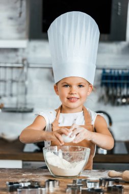 aron ve Şef şapkalı hamur pişirme ve kameraya gülümseyen sevimli çocuk