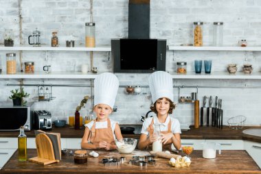 çok güzel çocuklar chef şapka ve kurabiye hamur hazırlama ve kameraya gülümseyen önlük 