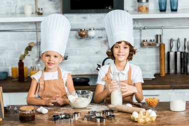 chef şapka ve önlük kurabiye hamur hazırlama ve kameraya gülümseyen sevimli küçük çocuklarda 