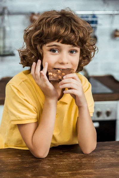 Menino Bonito Comendo Chocolate Com Avelãs Olhando Para Câmera — Fotografia de Stock Grátis