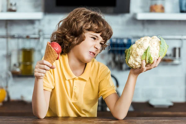 Несчастный Ребенок Держит Вкусное Сладкое Мороженое Здоровую Цветную Капусту — стоковое фото