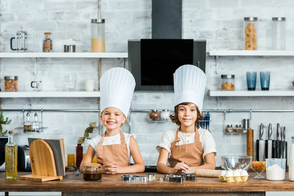 Adorabili Copii Fericiți Șorțuri Pălării Bucătar Zâmbind Cameră Timp Gătesc — Fotografie, imagine de stoc