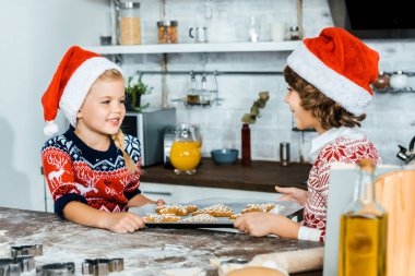 zencefil çerezleri fırın tepsisiyle holding ve diğer her gülümseyen santa şapkalar çok güzel mutlu çocuk