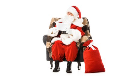 Noel Baba koltuk tablet ve uzak üzerinde beyaz izole seyir ile oturuyor
