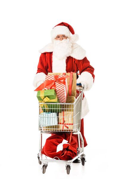 santa claus with shopping cart full of gift boxes looking at camera isolated on white