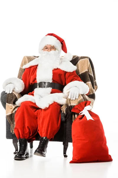 Santa Claus Siedzi Fotelu Ogląda Aparatu Białym Tle — Zdjęcie stockowe