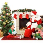 Happy kids and santa sitting in front of fireplace together isolated on white