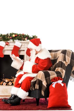 koltuk üzerinde beyaz izole şömine yakın içinde otururken Noel Baba okuma mektup