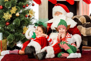 Onlar oturan şöminenin önünde birlikte kat iken mutlu çocuklar kucaklayan santa