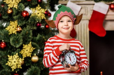 elf kostümü ile çalar saat ayakta Noel ağacı önünde çok güzel küçük çocuk