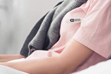 kadın yatakta elektronik termometre ile sıcaklık ölçme bardak kırpılmış
