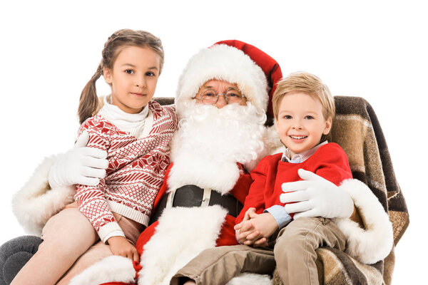 kids and santaembracing and looking at camera while sitting in armchair together isolated on white
