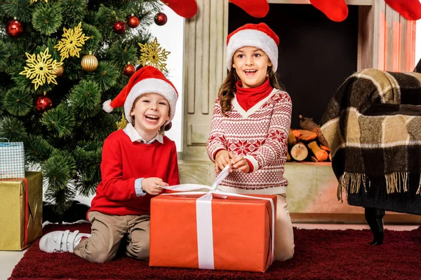 Happy Little Kids Opening Red Christmas Gift While Sitting Floor — Stock Photo, Image