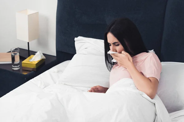 ナプキンが付いているベッドで横になっている咳の病気の若い女性 — ストック写真